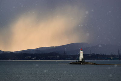 Lighthouse by sea against sky at night