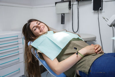 Portrait of smiling young woman sitting on dentist chair