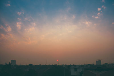 View of city against cloudy sky during sunset