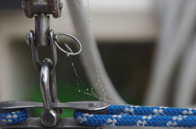 Close-up of spider web by rope with equipment