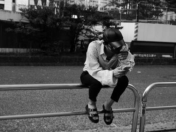 Rear view of women sitting on railing