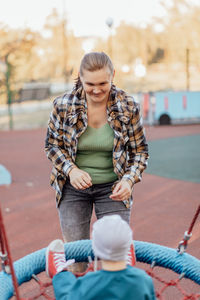 A little boy climbed up on the stairs to the slide with his mother