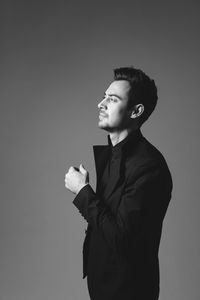 Portrait of young man looking away against gray background