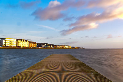 Pier by sea against sky during sunset