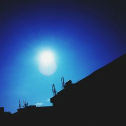 Low angle view of silhouette statue against blue sky