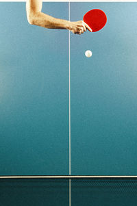 Tabletennis table with right forearm and white ball shot from above