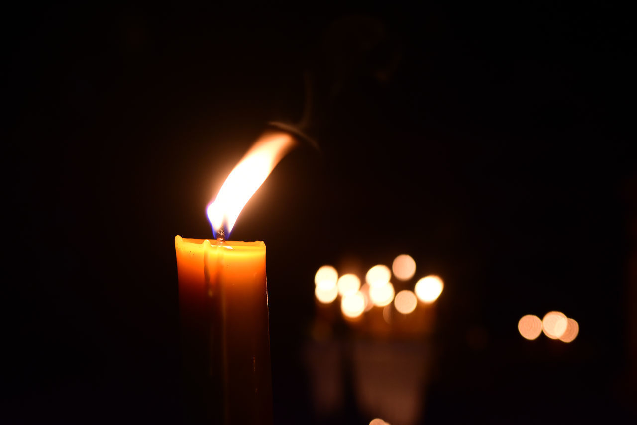 CLOSE-UP OF CANDLES BURNING IN DARKROOM