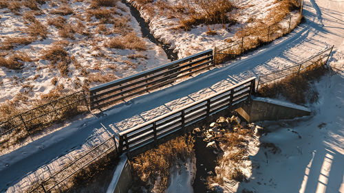 Public walking path in winter with snow and tracks. sun sets over the land with shadows.