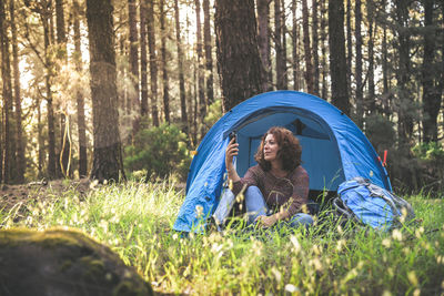 Woman sitting in tent at forest