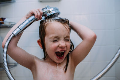 Close up of young girl rinsing shampoo from hair in shower