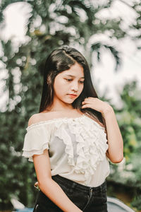 Happy young woman standing against tree