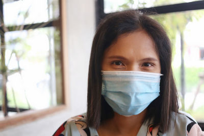 Close-up portrait of woman wearing mask sitting at home