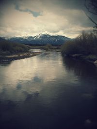 Scenic view of lake and mountains against cloudy sky
