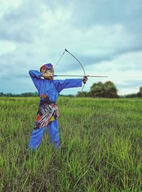 Side view of child standing on field with a bow and arrow like a malay worrior 