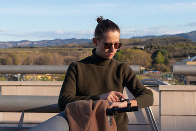 Close up portrait of man whearing a bun hairstyle and sunglasses using smart watch on wrist 