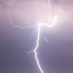 Low angle view of thunderstorm against cloudy sky at night