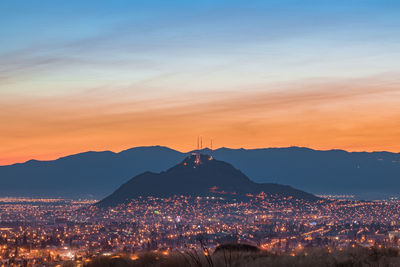 Illuminated cityscape against sky at sunrise