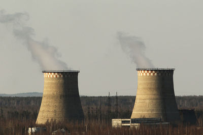 Smoke emitting from factory against sky