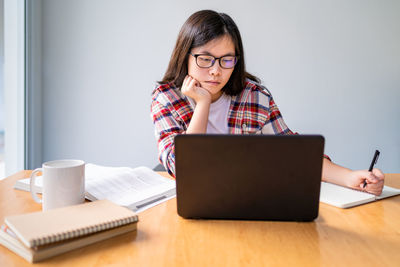 Mid adult woman using smart phone while sitting on table