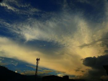 Low angle view of silhouette electricity pylon against dramatic sky