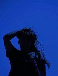 Portrait of woman standing against blue sky