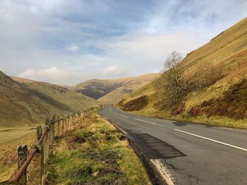 Road leading towards mountains against sky