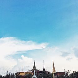 Birds flying over city against cloudy sky