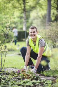 Full length portrait of smiling young man planting at garden