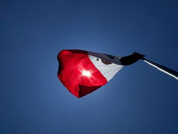 Low angle view of flag against clear blue sky