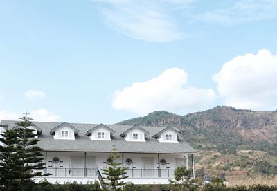 Houses by trees and mountains against sky