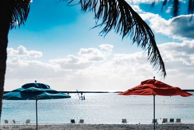 Beach umbrellas by sea against sky