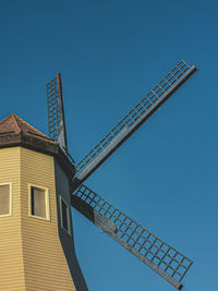 Low angle view of windmill against clear blue sky