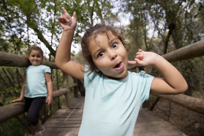 Portrait of siblings on footbridge against tree