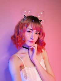 Portrait of young woman wearing headband against pink background