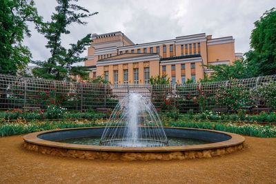 Fountain in garden against buildings in city