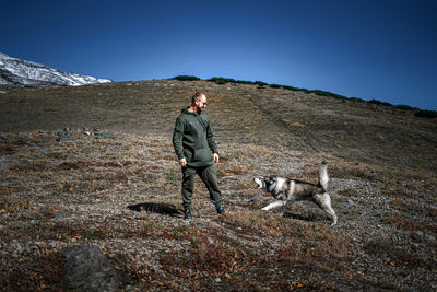 Full length of man with dog in mountains against clear sky