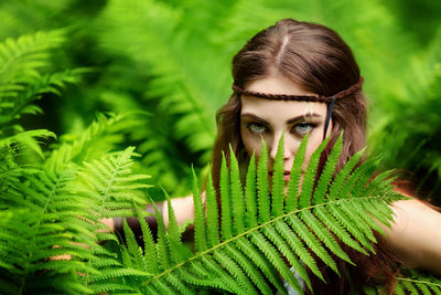 Portrait of young woman with plants fern