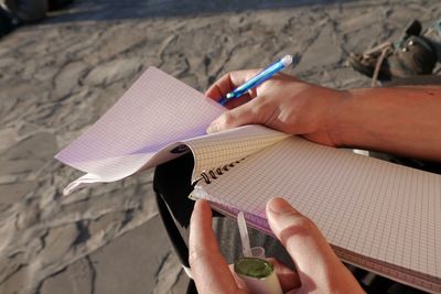 Close-up of woman holding book while sitting outdoors