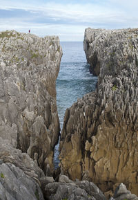 Rock formation on beach against sky