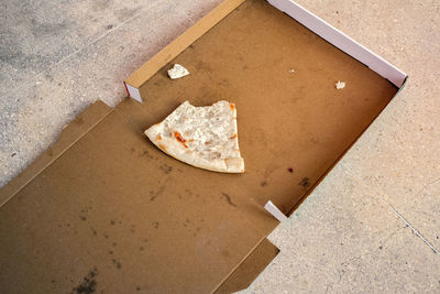 Empty pizza box with one scrap of a piece remains thrown on the street