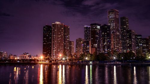 River by city skyline against sky at night