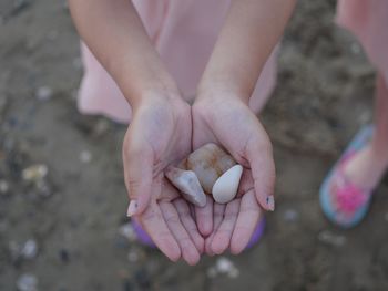 Low section of woman holding stones at beach