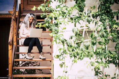 Full length of businesswoman using laptop while sitting on steps