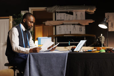 Young man using digital tablet while sitting on table