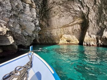 Boat sailing on sea by cliff