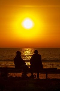 Silhouette of people on sea at sunset