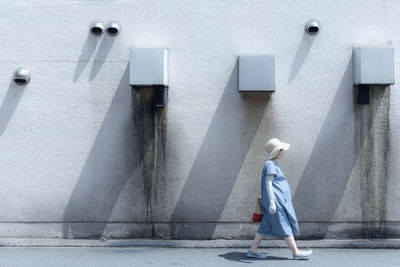Side view of woman walking against wall