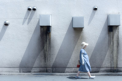 Rear view of man walking on footpath against building