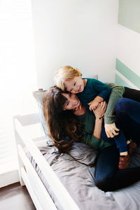 Young woman sitting on bed at home