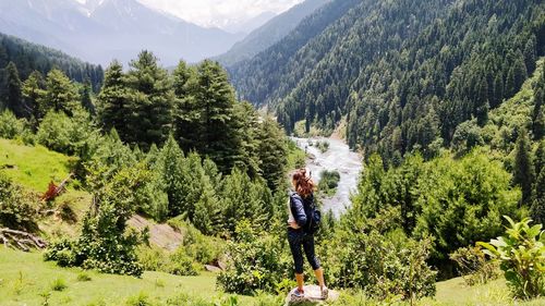 Woman standing against trees and mountains